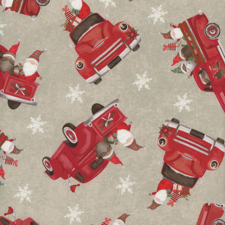 Tela 100 % algodón de color beige con motivos navideños: un camión y un gnomo, con el mensaje «Let It Snow»
