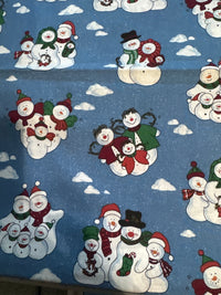 Diseño vintage con muñecos de nieve y nubes sobre fondo azul, 100 % algodón ligero. Precio por yarda.