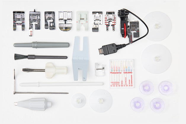 Collection of sewing machine attachments and tools on a white background