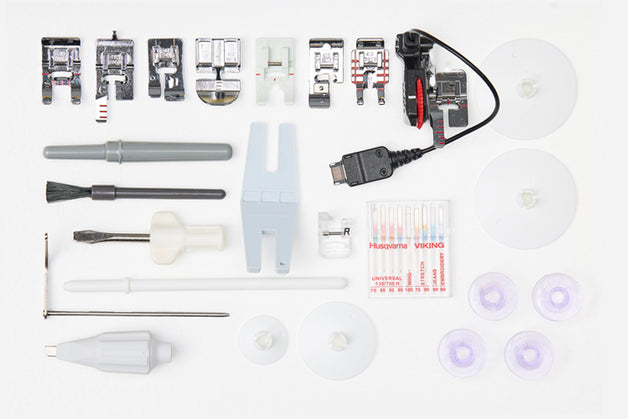 Collection of sewing machine attachments and tools on a white background