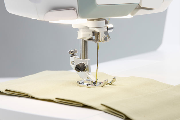 Close-up of a sewing machine needle in action on fabric.