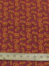 Tela de poliéster y algodón color burdeos con motivos de calabazas de Halloween